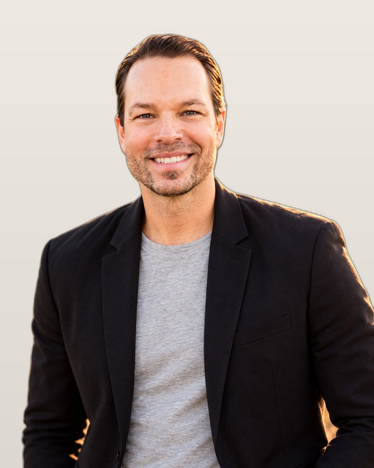 Dominic Bartola smiling in a black blazer against a clean light studio background