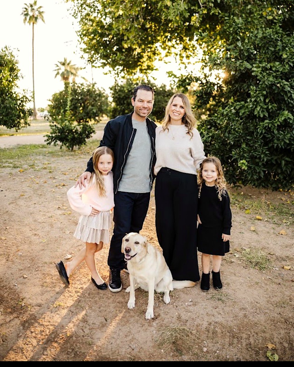 Dominic Bartola outdoors with his family, two daughters, and their yellow Labrador