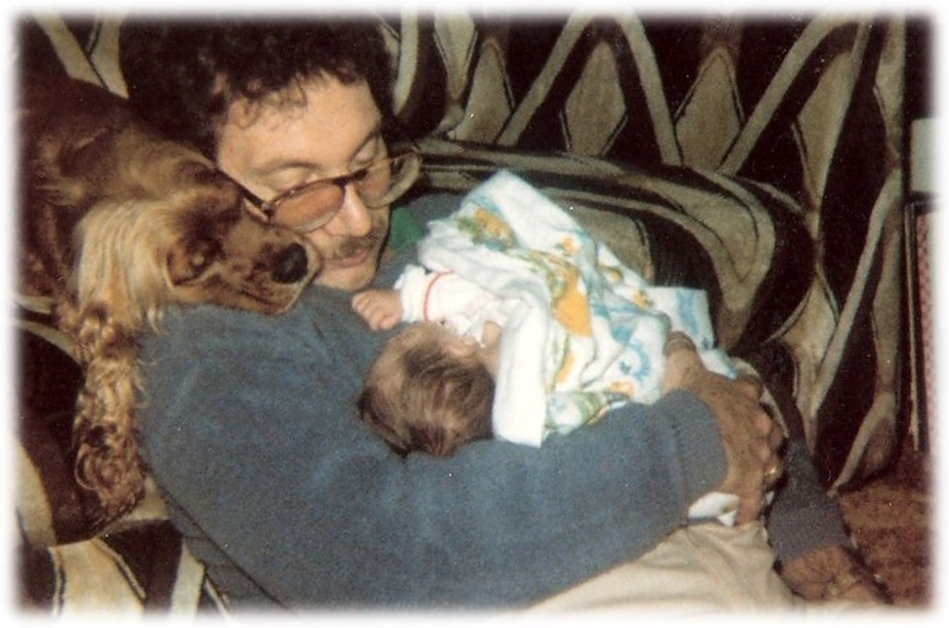 Dominic as a baby held by his father, with the family dog beside them